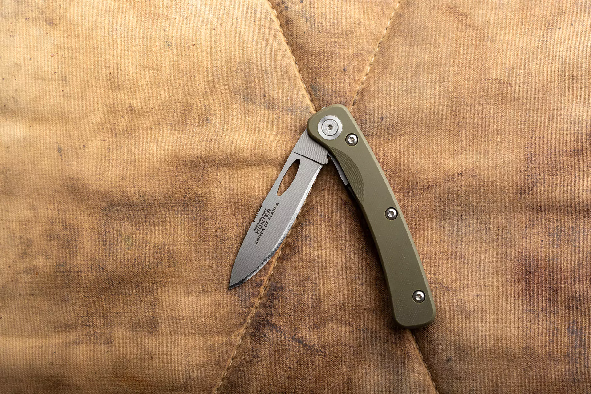 Featherlight Hunter folding knife with OD green G10 handle on waxed canvas