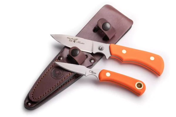 Trekker Series Elk Hunter and Cub Bear knives with orange Suregrip handles alongside a leather sheath.
