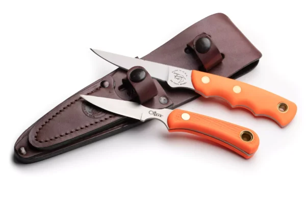 Knives of Alaska Cub Bear and Jaeger knives with orange Suregrip handles next to brown leather sheath.